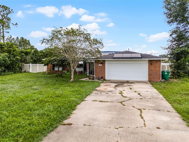 ranch-style house with a garage, a front lawn, and solar panels