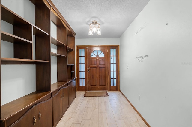 1005 Crescent Pkwy, Deland, FL 32724 - foyer entrance with baseboards, light wood-type flooring, a textured ceiling, and a chandelier