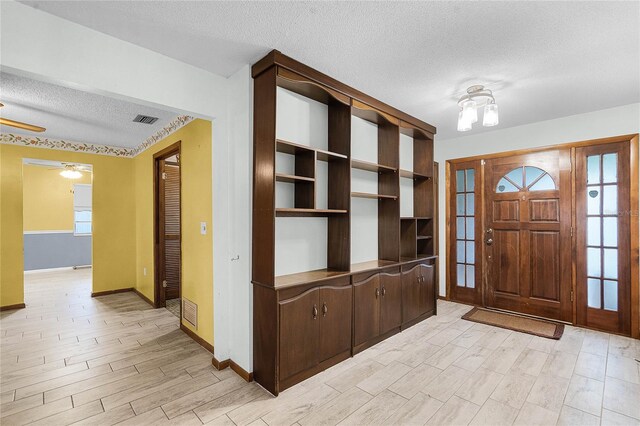 1005 Crescent Pkwy, Deland, FL 32724 - entryway with ceiling fan, a textured ceiling, visible vents, baseboards, and light wood-style floors
