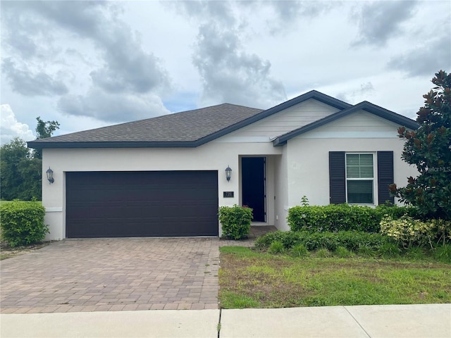 single story home featuring stucco siding, an attached garage, decorative driveway, and roof with shingles