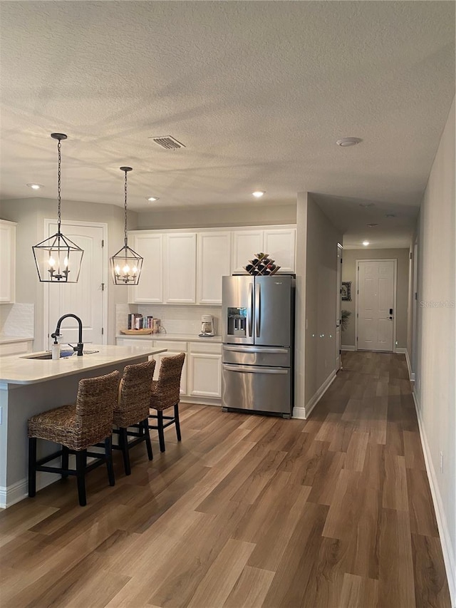 kitchen featuring stainless steel fridge, dark hardwood / wood-style flooring, a breakfast bar, sink, and white cabinets