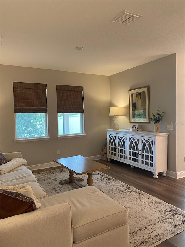 living room featuring dark wood finished floors, baseboards, and visible vents