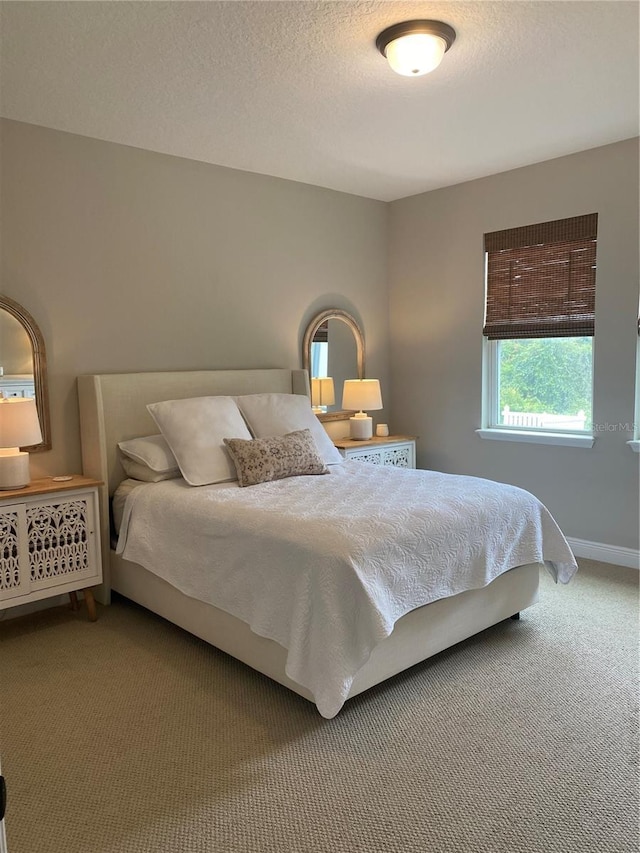 bedroom with a textured ceiling, carpet flooring, and baseboards