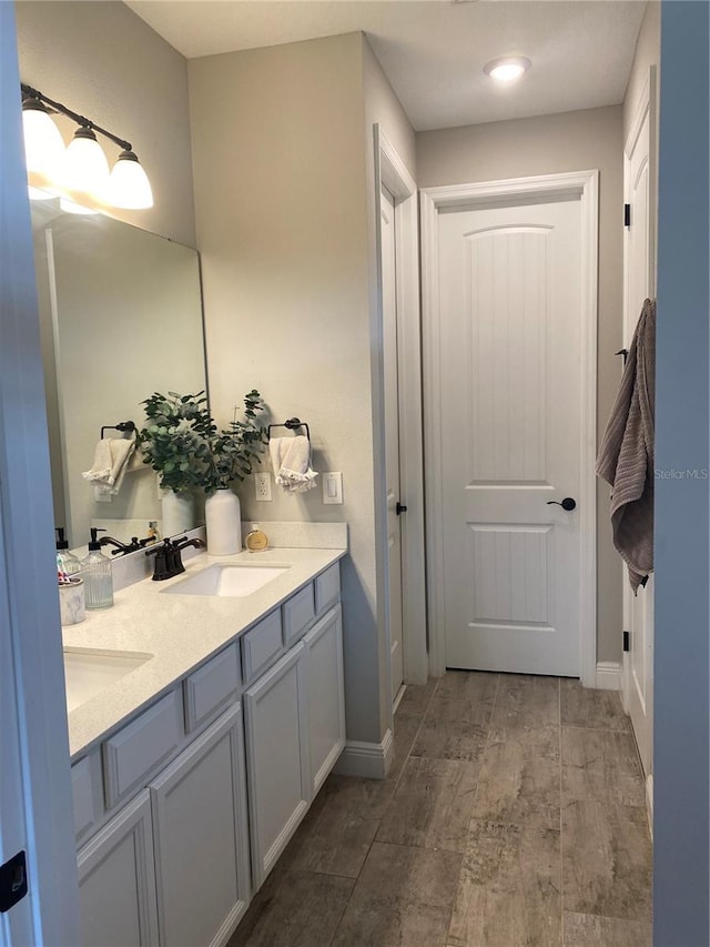 full bathroom featuring baseboards, a sink, and double vanity