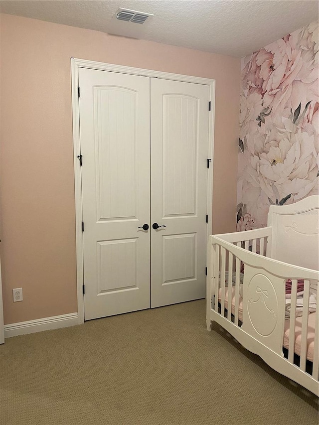 bedroom featuring a closet, visible vents, carpet flooring, and a textured ceiling