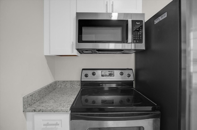 kitchen with light stone countertops, appliances with stainless steel finishes, and white cabinets