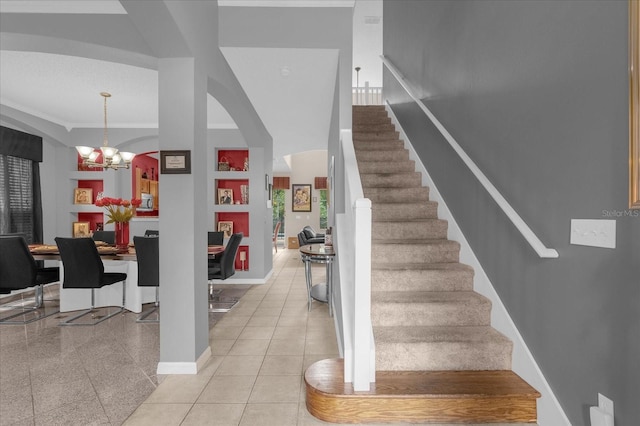 stairs featuring crown molding and an inviting chandelier