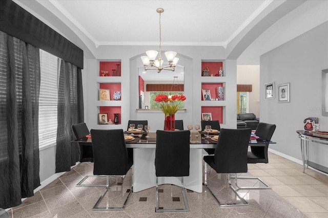 dining room with built in features, ornamental molding, and an inviting chandelier