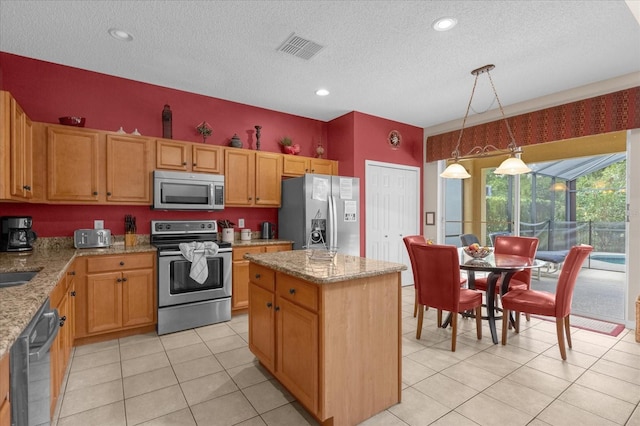 kitchen featuring pendant lighting, a kitchen island, stainless steel appliances, and light stone countertops