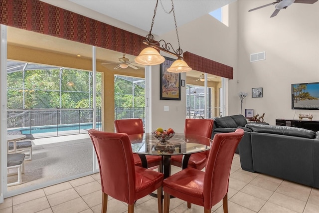 tiled dining space featuring ceiling fan and a high ceiling