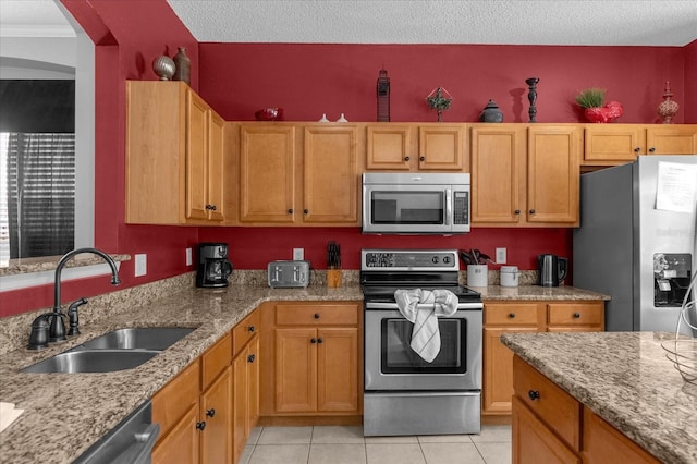 kitchen featuring sink, light stone countertops, appliances with stainless steel finishes, and light tile patterned flooring