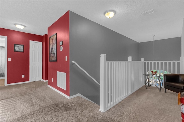 hall with a textured ceiling and carpet floors