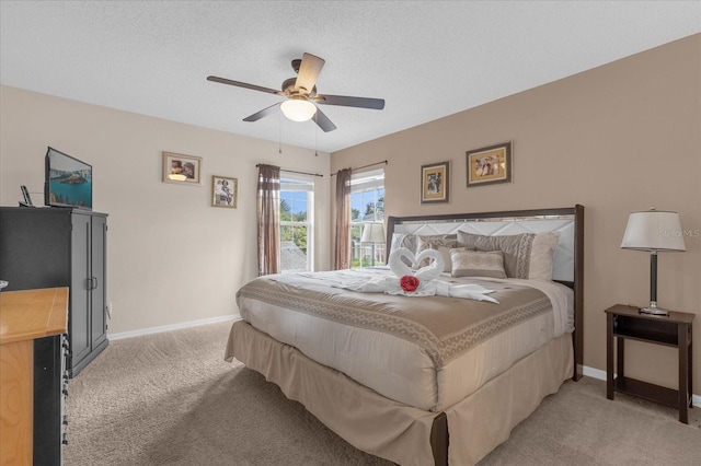 bedroom with a textured ceiling, light colored carpet, and ceiling fan