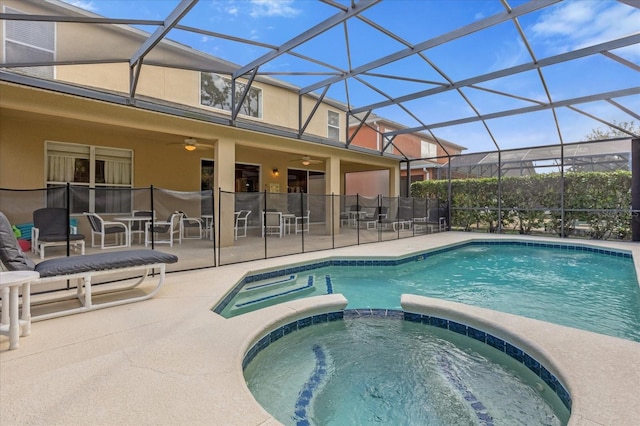 view of swimming pool featuring glass enclosure, ceiling fan, a patio area, and an in ground hot tub