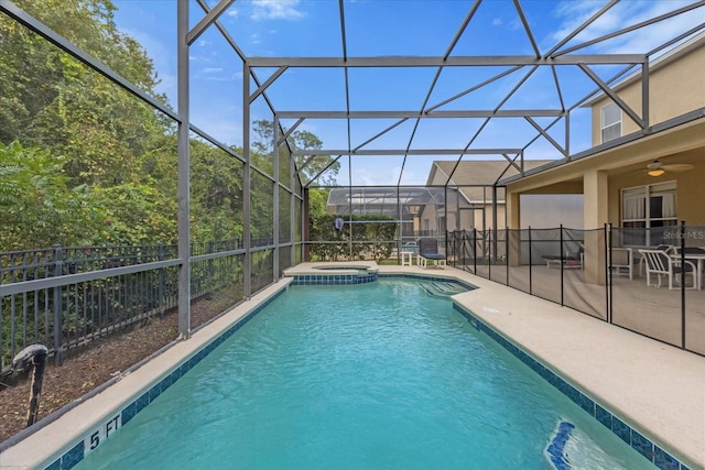 view of pool featuring glass enclosure, an in ground hot tub, ceiling fan, and a patio