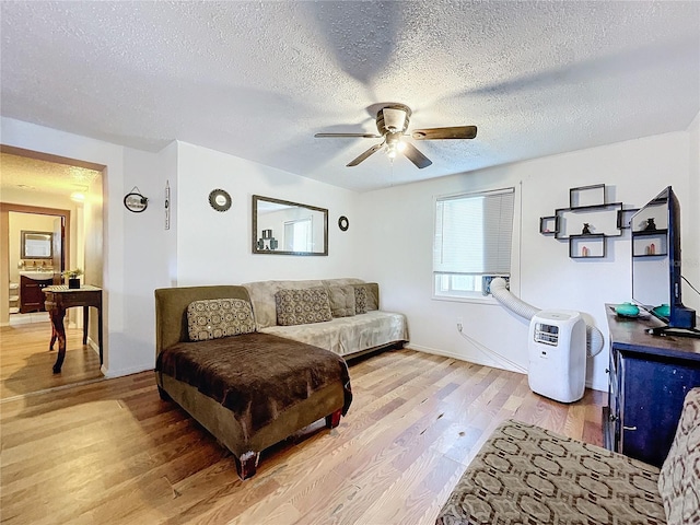 living room with light wood-type flooring, ceiling fan, and a textured ceiling