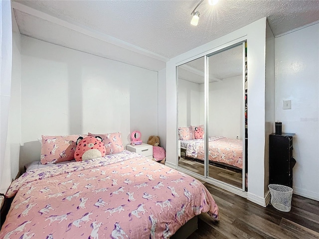 bedroom featuring a closet, dark hardwood / wood-style floors, and a textured ceiling