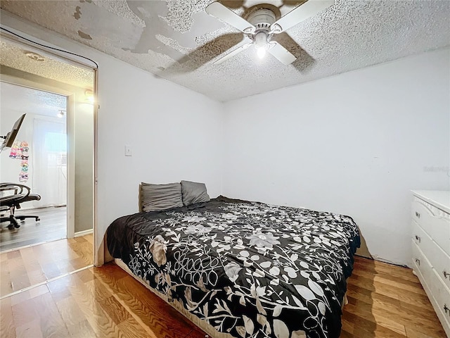 bedroom featuring a textured ceiling, wood-type flooring, and ceiling fan