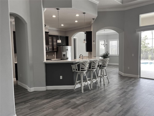 kitchen with kitchen peninsula, stainless steel fridge, hanging light fixtures, and dark hardwood / wood-style floors