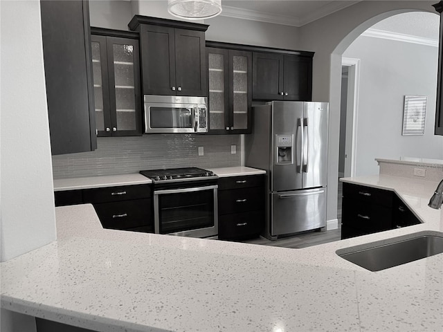 kitchen featuring sink, stainless steel appliances, tasteful backsplash, light stone counters, and crown molding