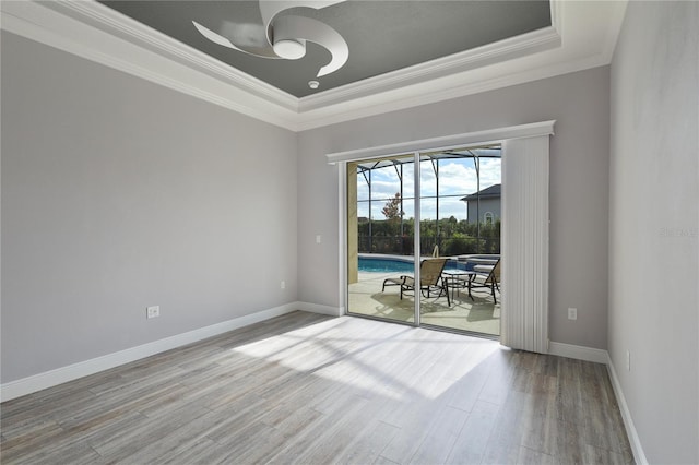 empty room with ceiling fan, light hardwood / wood-style floors, a raised ceiling, and ornamental molding