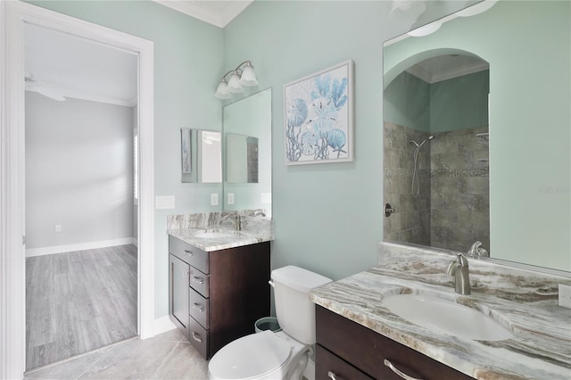 bathroom featuring tile patterned floors, a tile shower, vanity, crown molding, and toilet