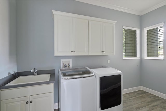 laundry room with cabinets, light wood-type flooring, ornamental molding, sink, and independent washer and dryer