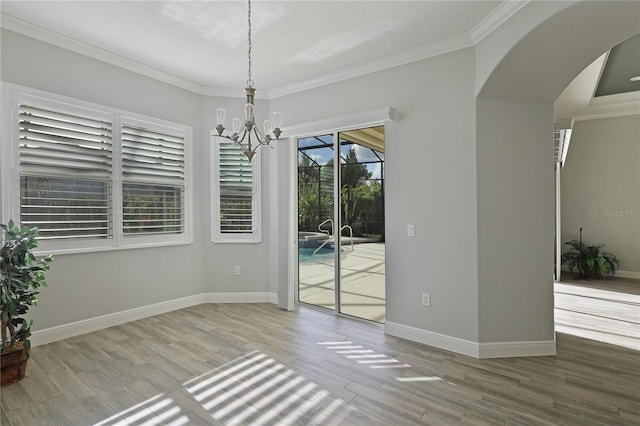 empty room featuring wood-type flooring, crown molding, and an inviting chandelier