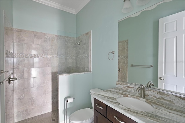 bathroom with tiled shower, crown molding, vanity, and toilet