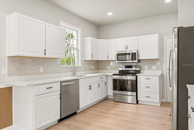 kitchen with light wood finished floors, appliances with stainless steel finishes, backsplash, and a sink