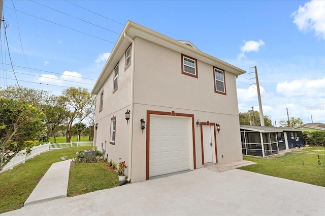 view of side of property featuring a lawn, a sunroom, an attached garage, fence, and stucco siding