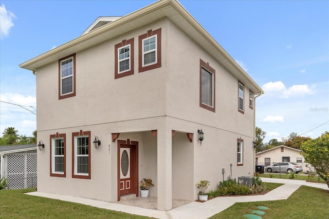 view of front facade with central air condition unit, a front yard, and stucco siding