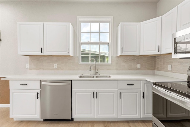 kitchen with appliances with stainless steel finishes, white cabinetry, a sink, and decorative backsplash