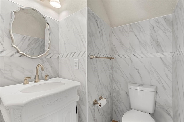 bathroom with a textured wall, vanity, and toilet