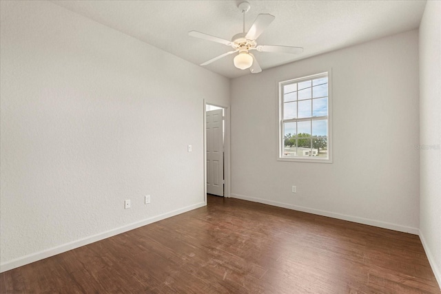 spare room with dark wood finished floors, baseboards, and ceiling fan