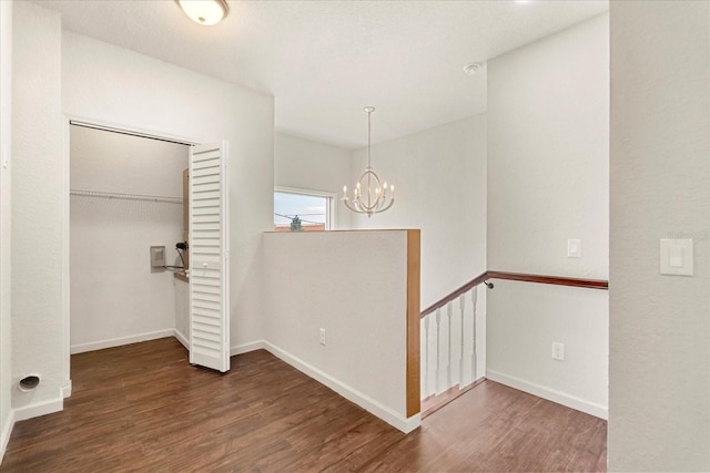 spare room featuring baseboards, an inviting chandelier, and wood finished floors