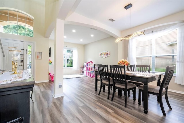 dining room featuring wood finished floors, arched walkways, baseboards, visible vents, and recessed lighting