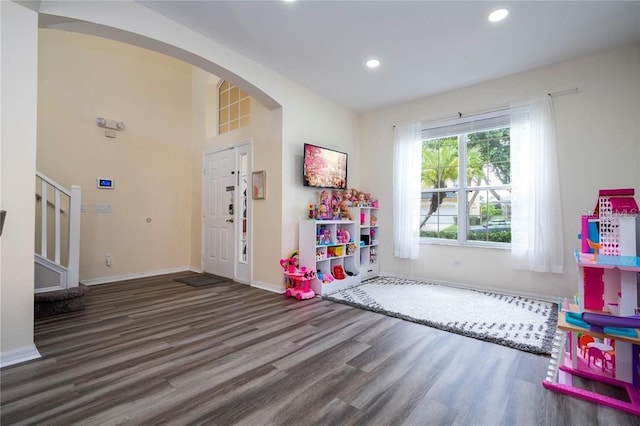 game room featuring recessed lighting, arched walkways, wood finished floors, and baseboards