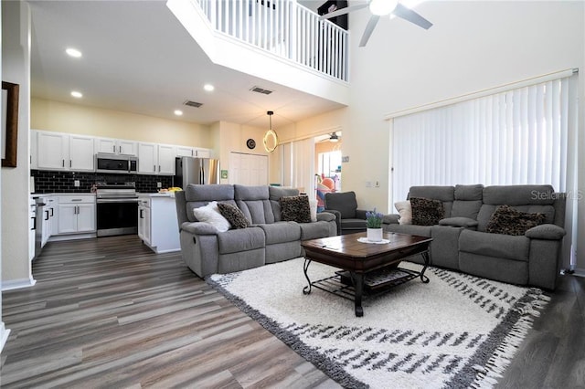 living room featuring a high ceiling, ceiling fan, and dark hardwood / wood-style floors