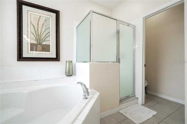 full bath featuring toilet, baseboards, tile patterned flooring, a shower stall, and a garden tub