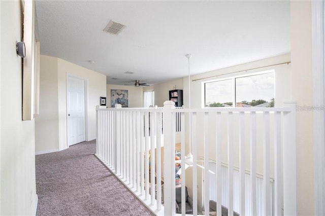 corridor featuring baseboards, visible vents, and carpet flooring