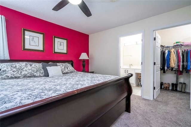 bedroom with a ceiling fan, ensuite bathroom, a closet, a walk in closet, and light carpet