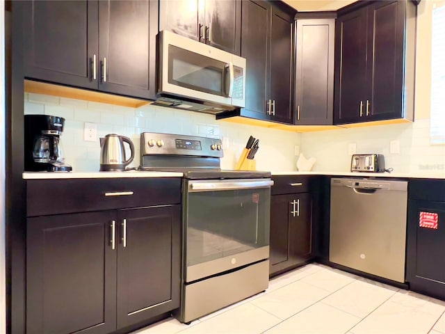 kitchen featuring light tile patterned floors, backsplash, stainless steel appliances, and dark brown cabinetry