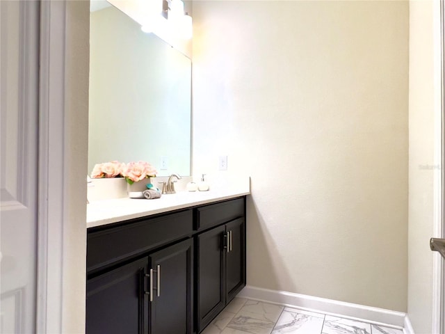 bathroom with marble finish floor, vanity, and baseboards