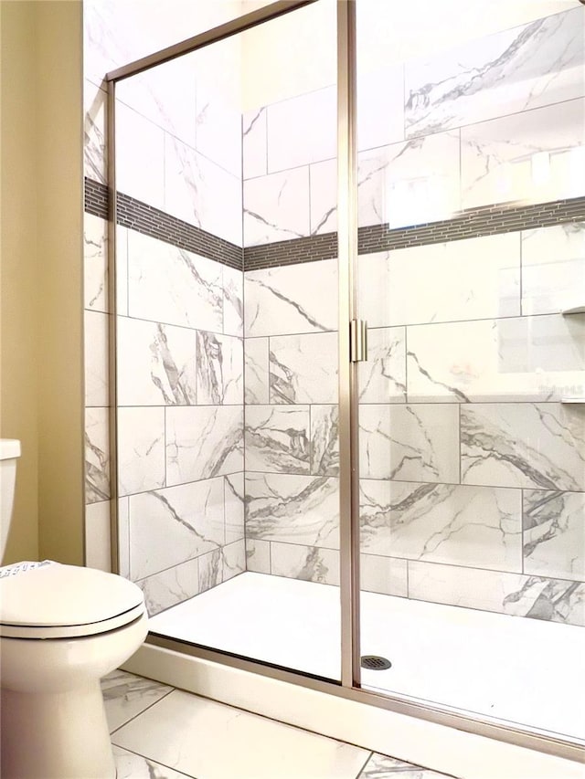 full bathroom featuring a shower stall, toilet, and marble finish floor