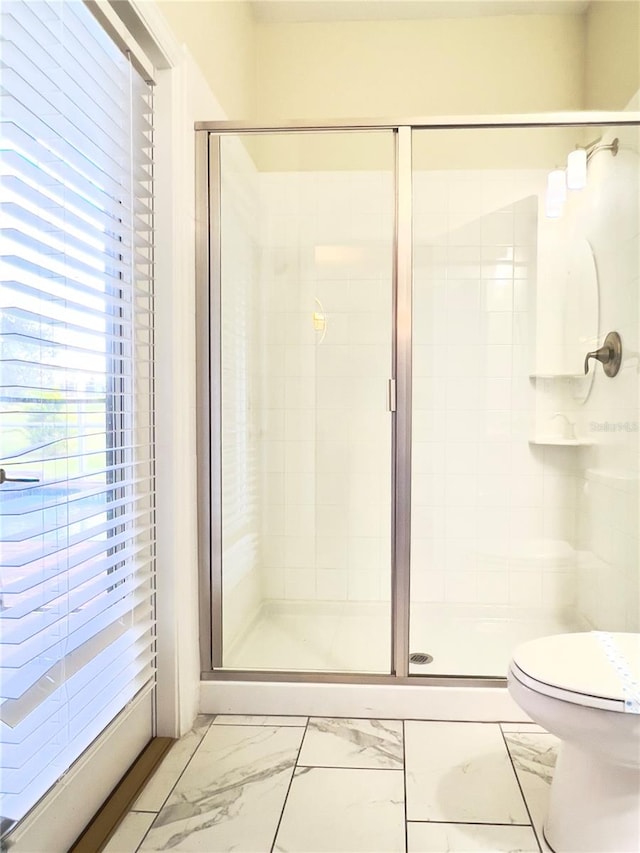 bathroom featuring toilet and a shower with door