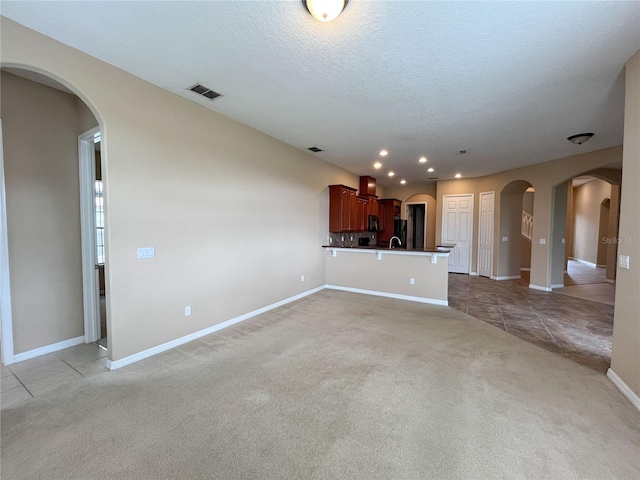 unfurnished living room with light carpet and a textured ceiling