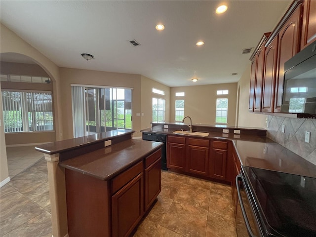 kitchen featuring kitchen peninsula, decorative backsplash, sink, and black appliances