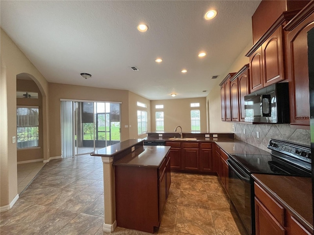 kitchen with kitchen peninsula, tasteful backsplash, a textured ceiling, sink, and electric range