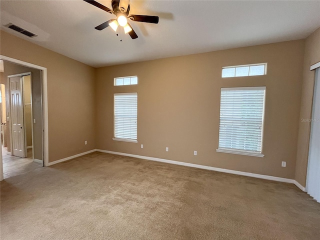 carpeted spare room with ceiling fan and plenty of natural light